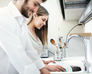 Couple washing dishes at house sink
